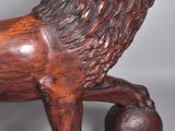 wooden sculpture of a lion on a ball on a grey background