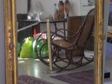 a large mirror in the middle of a room with a rocking chair in it