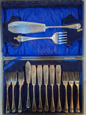 des couverts dans une boîte recouverte d'un tissu bleu, comprenant une fourchette, un couteau, une cuillère et un repose-cuillère