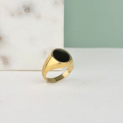 gros plan d'une bague en or contenant une pierre noire