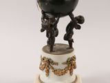 an antique figurine of a boy holding a ball on top of a pedestal