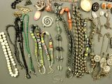 many different necklaces and bracelets that are on a table