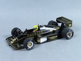 la maquette d'une voiture de course noire et dorée posée sur une surface blanche