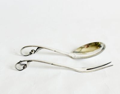 une cuillère en argent et un repose-cuillère posés sur une surface blanche