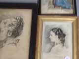 quatre portraits de femmes encadrés, réalisés dans différents styles artistiques, accrochés au mur
