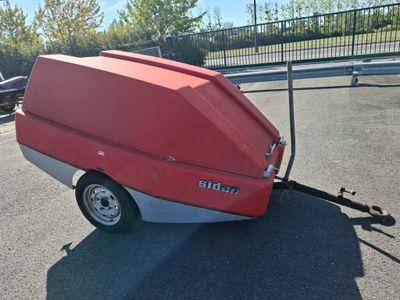 a small red truck with a trailer attached to it ' s back