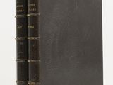 un livre marron posé sur une table blanche, près d'un mur blanc