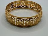 gros plan d'un bracelet en or sur une surface blanche