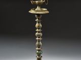 une vieille lampe en laiton surmontée d'un oiseau