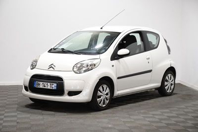 La petite voiture blanche est garée dans une pièce dont le sol est en damier.
