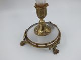a gold candle holder with a glass candle on top of it