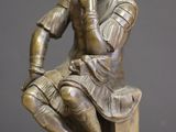 a bronze statue of a man sitting on a pedestal