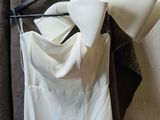 a white dress hanging on a hanger next to a coat