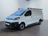 La camionnette blanche est garée dans une grande pièce où la lumière est allumée.