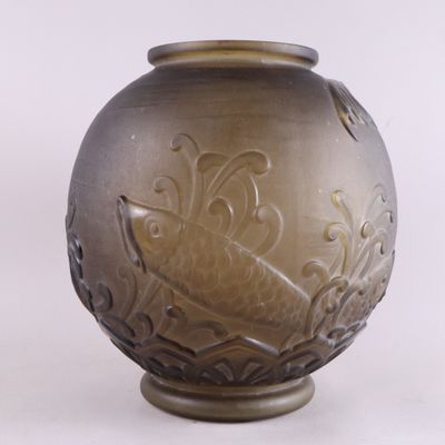 un vase brun orné d'un motif sur une surface blanche