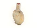 un petit vase posé sur une surface blanche