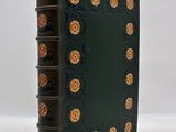 a green book with gold flowers on it sitting on a white surface