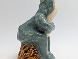 a ceramic frog that is sitting on top of a piece of wood