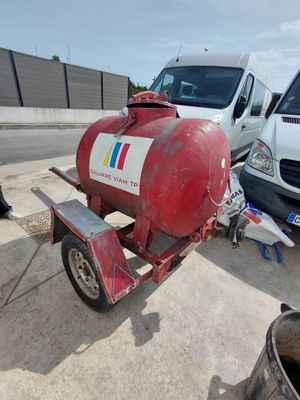 a red propanent on a trailer with a white van in the background