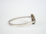 silver ring with a black stone in the middle of it on a white surface