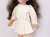 une vieille poupée en porcelaine aux longs cheveux, vêtue d'une robe blanche