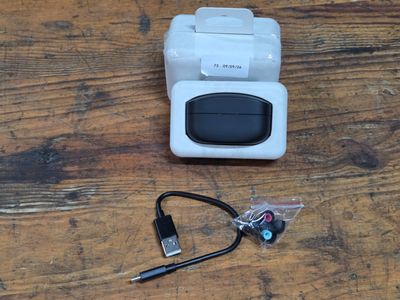 a small white device sitting on a table next to a pair of ear buds