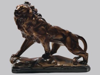 statue en bronze représentant un lion perché sur un rocher, sur fond gris