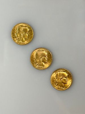 three gold coins are shown on a white surface with a white background