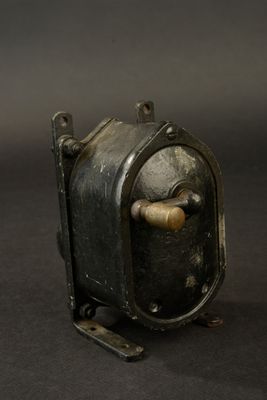 a small metal object with a wooden handle on a black surface