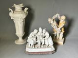 trois figurines posées sur une table à côté d'un vase
