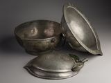 a silver bowl with a lid and a spoon with a leaf on it