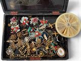 une boîte noire remplie de bijoux variés, posée sur une surface blanche