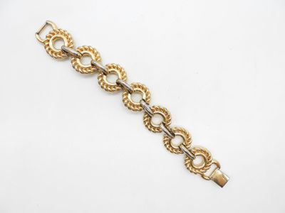 gros plan d'un bracelet en or sur une surface blanche