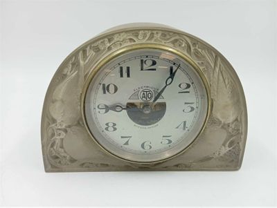 une horloge en argent posée sur une table blanche