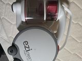un aspirateur blanc et rouge posé sur un lit, muni d'un cordon rouge
