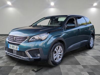 Un SUV bleu est garé dans une grande pièce au sol carrelé.