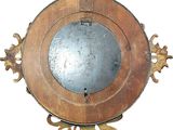 a wooden clock with a circular mirror in the middle