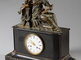 une statue de femme assise sur une table avec une horloge