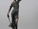 une statue antique en bronze représentant une femme tenant un chien