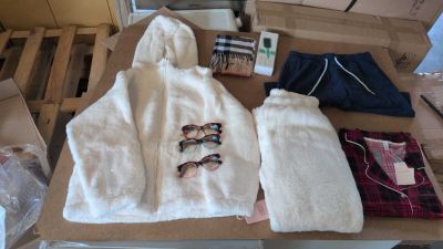 un tas de vêtements posé sur une table, sur laquelle se trouvent une paire de lunettes