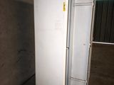 two white refrigerators in a room with a wall behind them