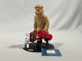 a figurine of a man sitting on a bench with a suitcase and a dog