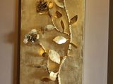 un tableau accroché au mur d'une pièce, représentant une rose dorée