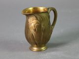 an antique brass pitcher on a gray surface