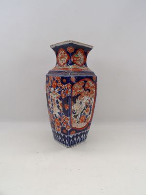 un vase bleu et orange posé sur une surface blanche