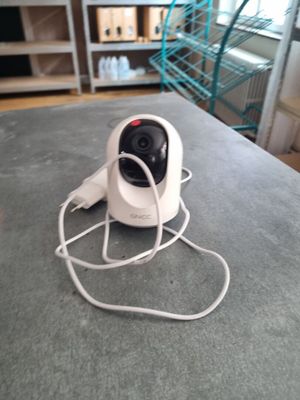 a white camera sitting on top of a table next to a book shelf