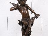 une statue antique en bronze représentant un Cupidon tenant une épée, posée sur un socle en marbre