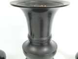 three black vases sitting on a white surface