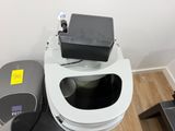 a white toilet with a black seat next to a black trash can