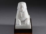 a white statue of a sphinx sitting on a wooden base